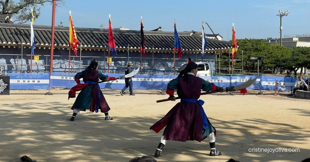Two performers in costume with curved-blade polearms during a Muye24gi martial arts demonstration at Suwon Hwaseong Fortress