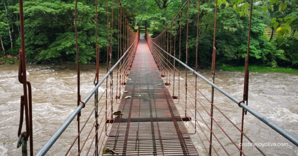 Red suspension bridge over a fast-flowing river in Tibiao, Antique